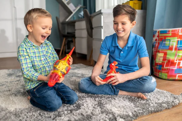 Two boys with rubber animal figures sitting on the floor — Stock Photo, Image