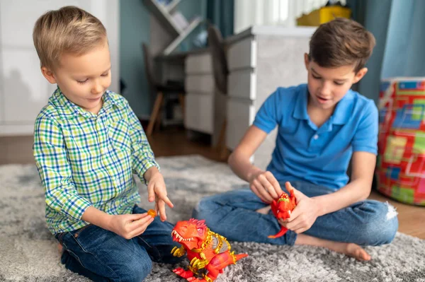 Two kids concentrated on their toy dinosaurs — Stock Photo, Image