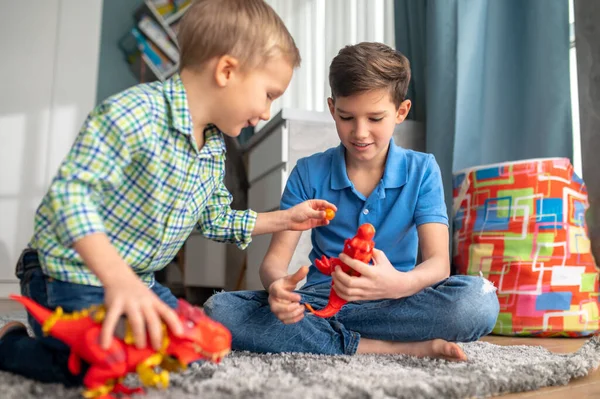 Two children playing with rubber animal figures — Stock Photo, Image