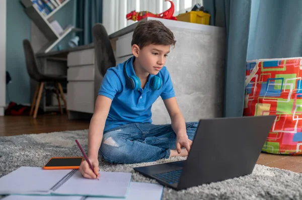 Niño enfocado sentado en su computadora portátil durante la lección en línea — Foto de Stock