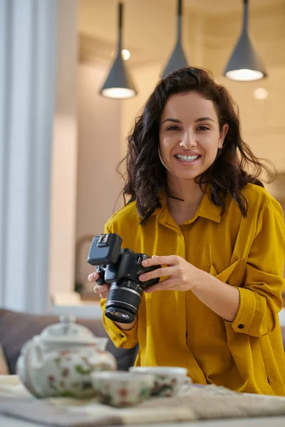Fiatal női fotós mustáros ingben, fényképezőgéppel a kezében — Stock Fotó
