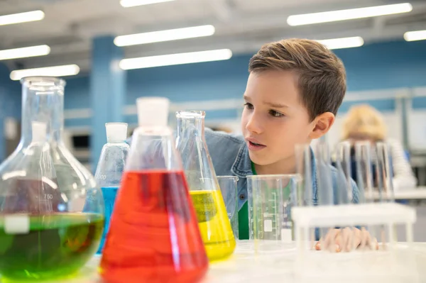 Çocuk renkli sıvılarla mataraları inceliyor.