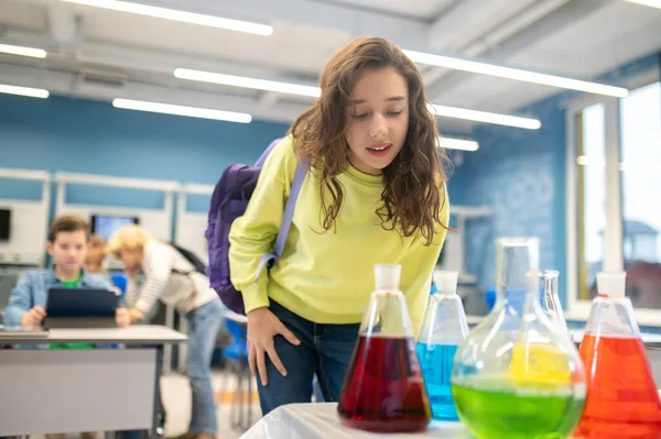 女孩在教室里靠在实验室的瓶子上 — 图库照片