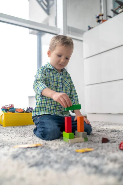 Kreativer kleiner Junge baut eine Baustruktur aus Spielzeugklötzen — Stockfoto