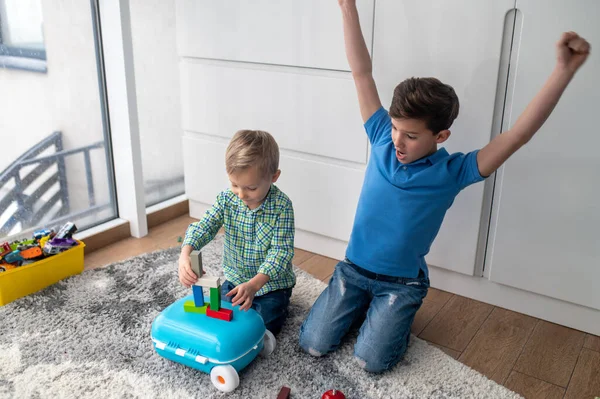 Teenager encouraging his younger sibling during the construction game — Stock Photo, Image