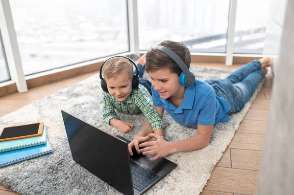 Dos niños con auriculares escuchando música en el ordenador — Foto de Stock