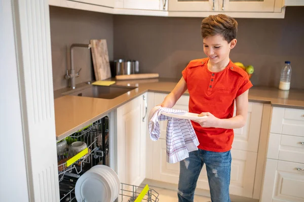 Fokuserad pojke torkar tvättade tallrikar med en handduk — Stockfoto