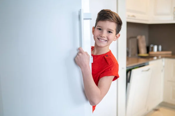 幸せな少年は外を見るオープン冷蔵庫のドア — ストック写真