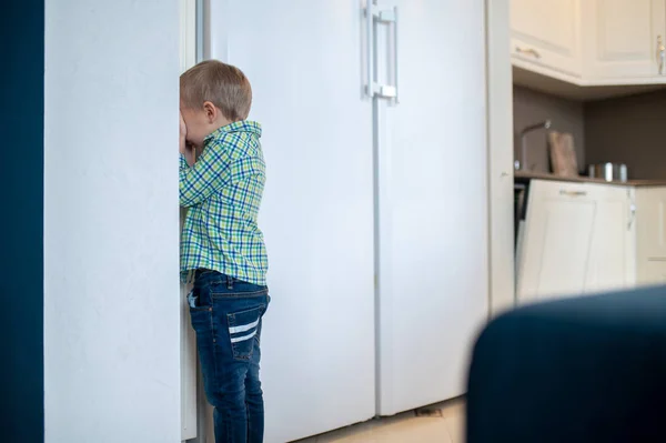 Chłopiec bawi się w chowanego w kuchni. — Zdjęcie stockowe