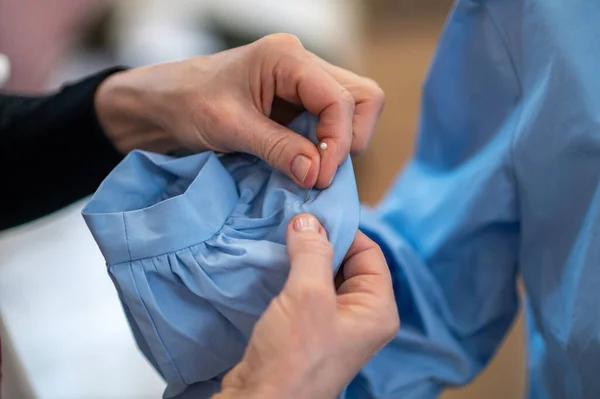 Manos de sastre con pasador perforante manga de blusa — Foto de Stock