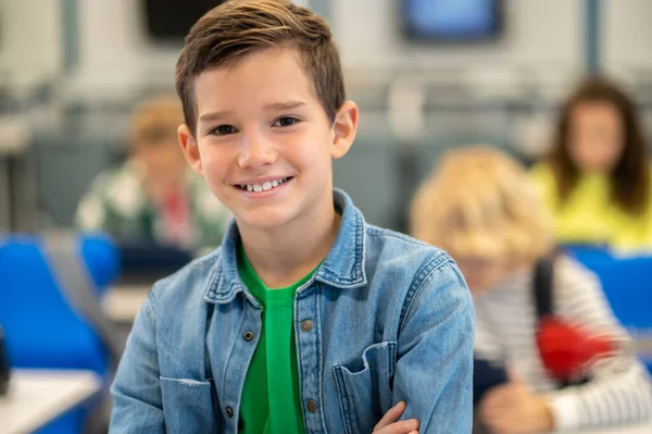 Chłopiec uśmiecha się pewnie do kamery w klasie — Zdjęcie stockowe