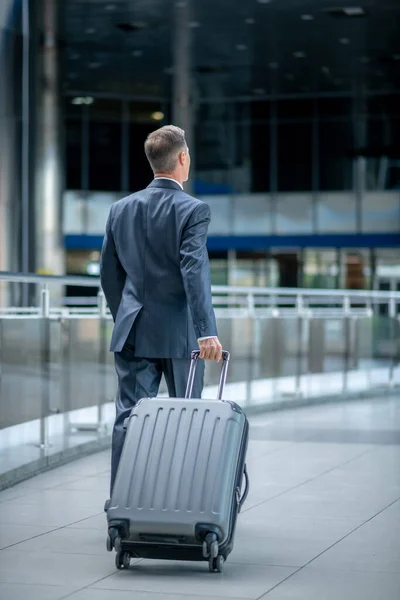 Man loopt met koffer met rug naar camera — Stockfoto