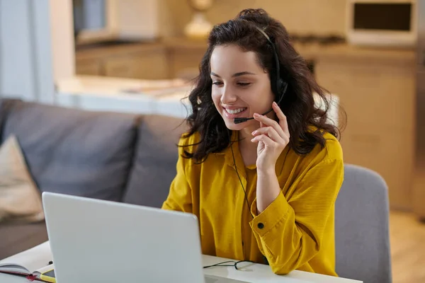 Aranyos fiatal nő mustáros ingben ül a laptopnál. — Stock Fotó