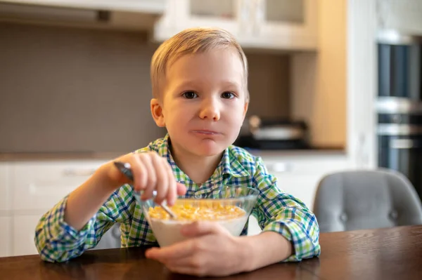 Спокійна дитина їсть сніданок і дивиться вперед — стокове фото