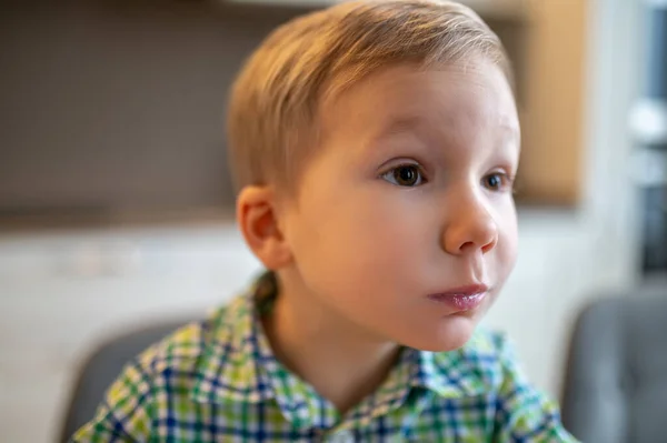 Verrast jongen zit met zijn mond vol kijken naar iets — Stockfoto