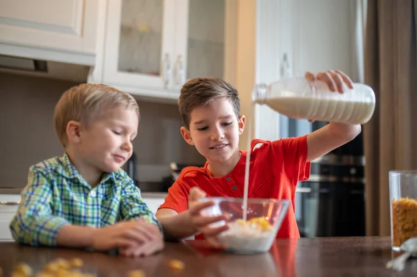 集中した子供作る朝食シリアルのために彼の兄 — ストック写真