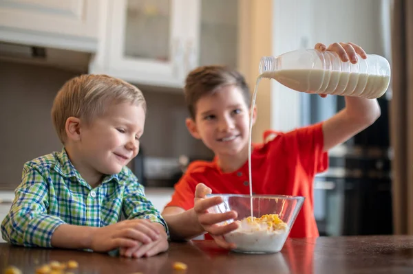 Menino alegre preparando café da manhã para seu irmão mais novo — Fotografia de Stock