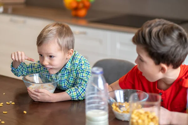 Verblüfftes Kind starrt auf sein Geschwisterchen, das sein Frühstück verschluckt — Stockfoto