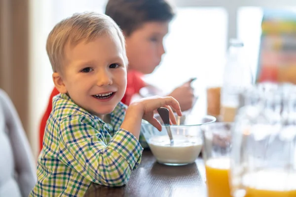 Rapaz alegre com uma tigela de cereais de pequeno-almoço olhando para a frente — Fotografia de Stock