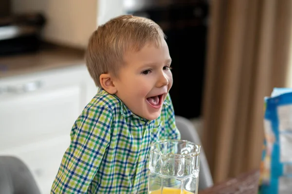 Kind mit offenem Mund lehnt auf dem Küchentisch — Stockfoto