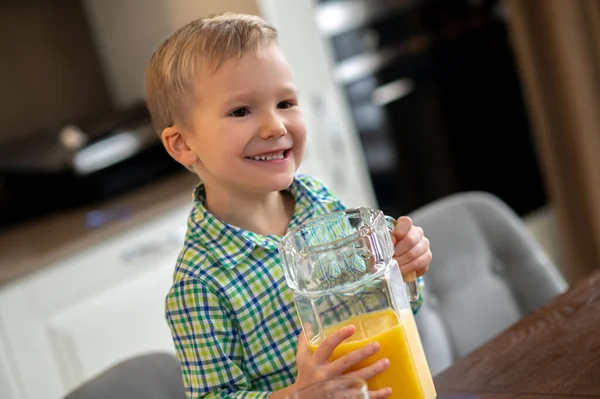 陽気な少年は柑橘類の飲み物でジャグを上げる — ストック写真