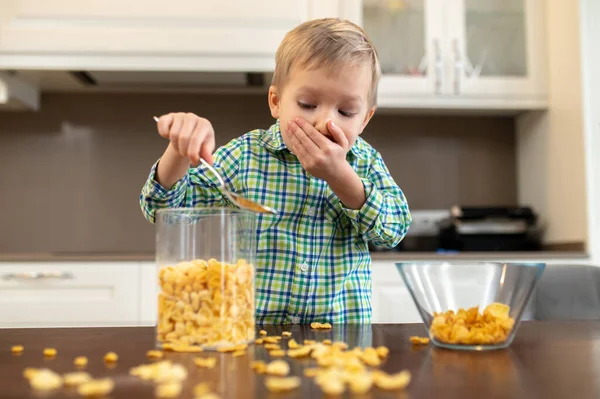 Niño confundido mirando los cereales del desayuno esparcidos por la mesa — Foto de Stock
