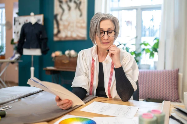 Woman sitting at table looking at sketch — Stock Photo, Image