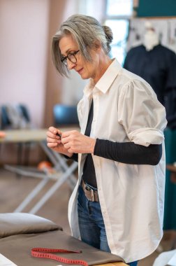 Masadaki kumaşa bakan bir kadın.