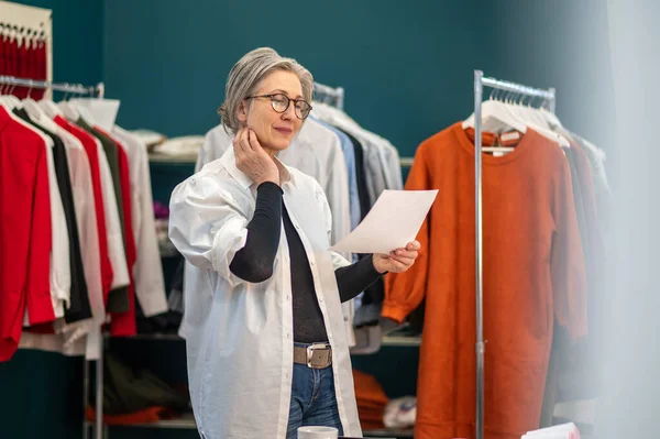 Vrouw kijkt naar stuk papier in de hand — Stockfoto