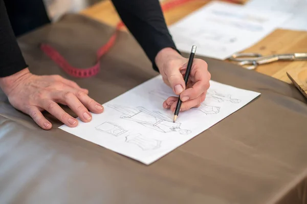 Mãos desenhando esboço de roupas com lápis sobre papel — Fotografia de Stock
