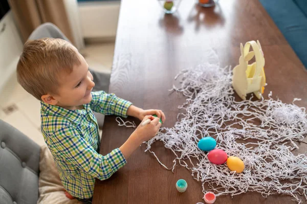 Little kid painting Easter eggs in the kitchen — Stock Photo, Image