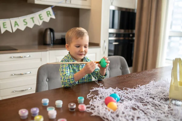 Focused creative boy decorating eggs for Easter — Stock Photo, Image