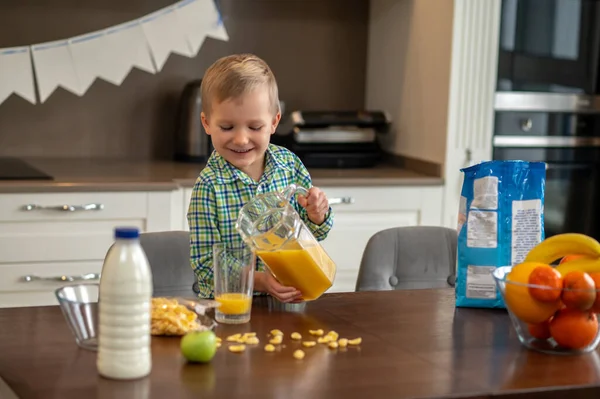 Freudiger Junge füllt sein Glas mit einem Fruchtgetränk — Stockfoto