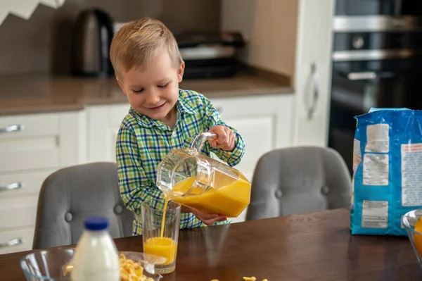 Criança derramando um suco de frutas do jarro — Fotografia de Stock