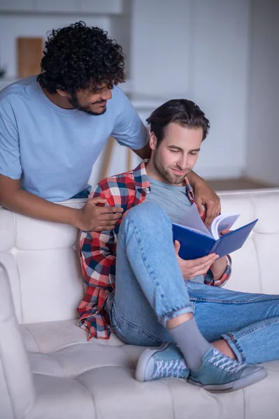 Maschio sorridente che abbraccia un giovane con un libro di testo — Foto Stock