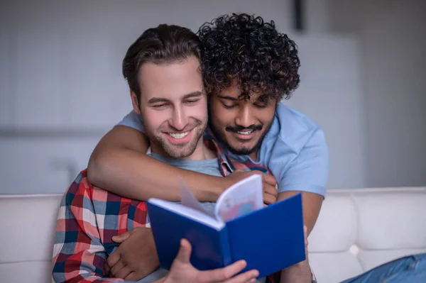 Hombre con un libro de texto abrazado por su novio romántico — Foto de Stock