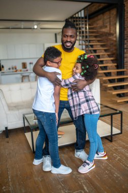 Odada dikilen çocuklara sarılan adam.