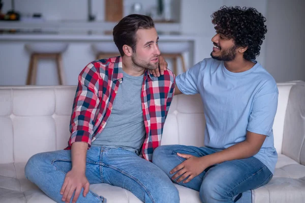 Biracial gay coppia avendo un conversazione su il divano — Foto Stock
