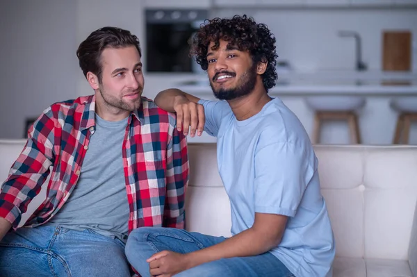 Romântico biracial gay casal sentado no o sofá — Fotografia de Stock