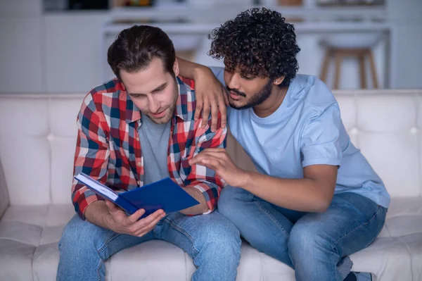 Biracial gay casal lendo um livro juntos — Fotografia de Stock