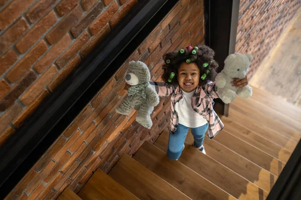 Вид сверху на девочку, показывающую игрушки на камеру — стоковое фото