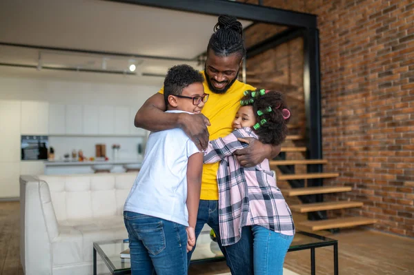 Hombre abrazando chico y chica de pie en casa —  Fotos de Stock
