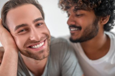 Kıvırcık saçlı adam yakışıklı erkek arkadaşına bakıyor.