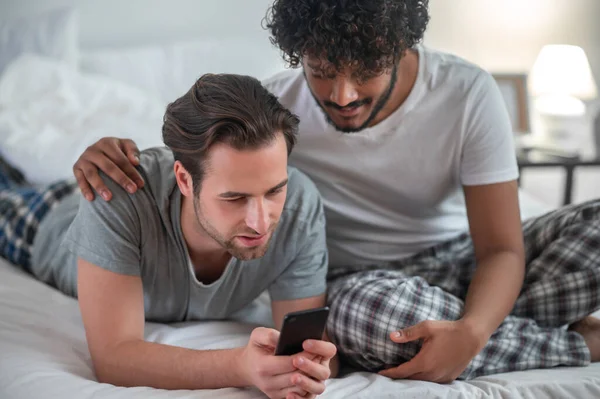 Dois homens concentrados olhando para a tela do celular — Fotografia de Stock