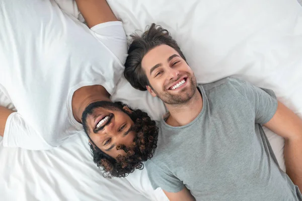 Feliz gay pareja posando para la cámara en cama —  Fotos de Stock