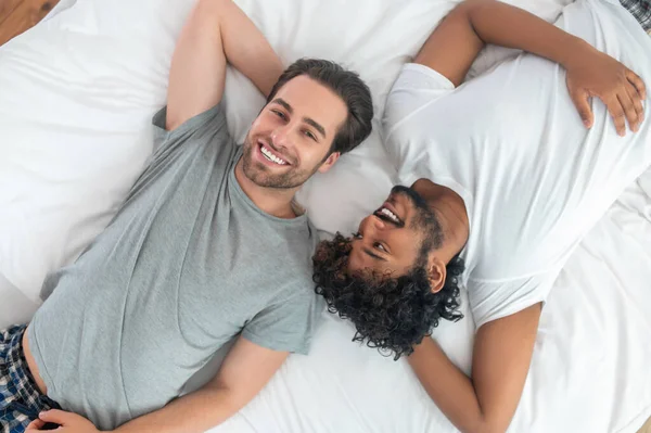 Romantic biracial gay couple resting in bed — Stock Photo, Image