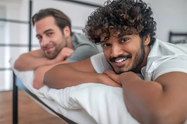 Jovem biracial gay casal deitado no cama — Fotografia de Stock