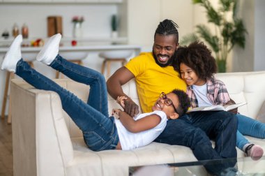 Gülen oğlu ve kucaklayan kızı olan baba.