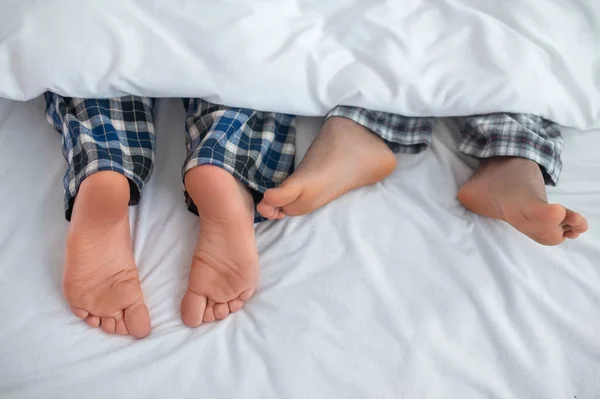 Pareja gay con los pies desnudos descansando en su dormitorio — Foto de Stock