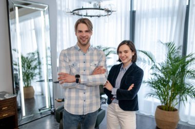 Ekose gömlekli bir adam kuafördeki kuaförle konuşuyor.